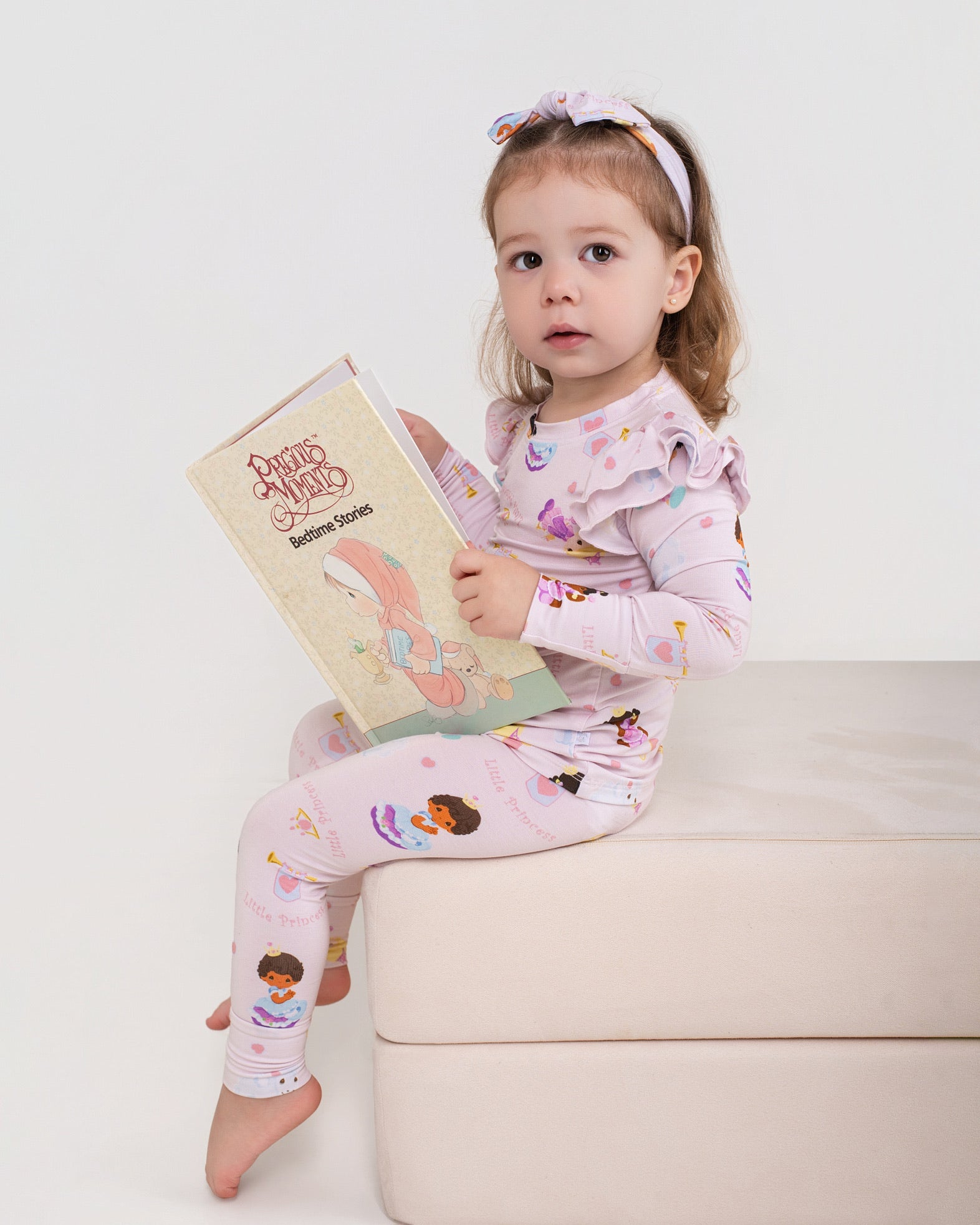 Child in pajamas holding a book on a white background